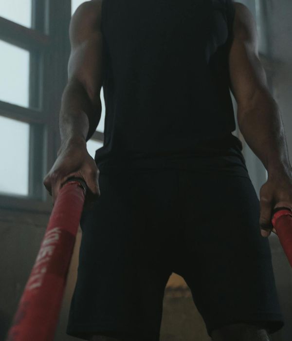 Man performing a controlled strength exercise in a dark gym setting.